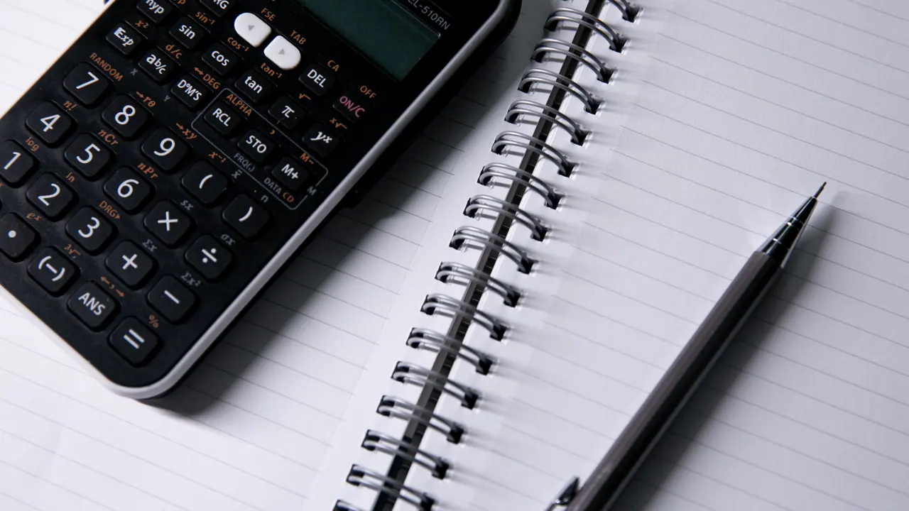 Calculadora preta e caneta sobre um caderno de páginas pautadas.