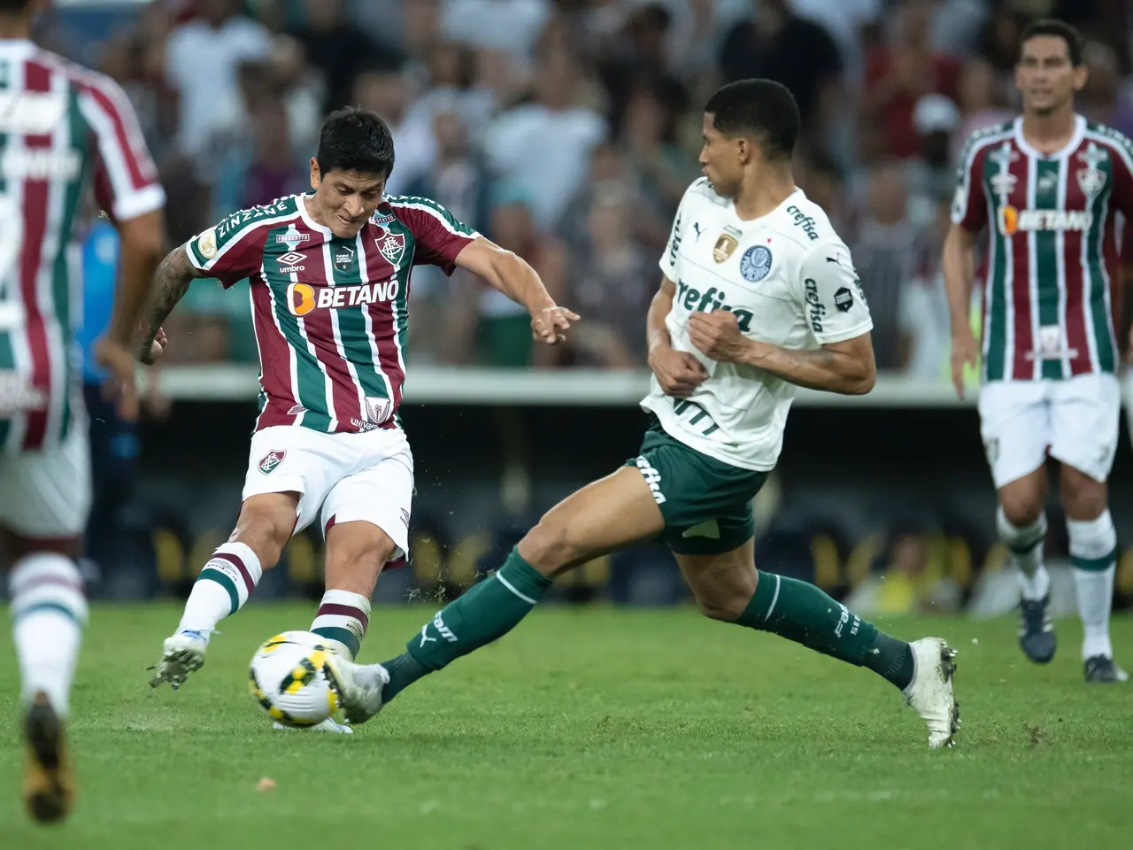 Jogadores do Fluminense e do Palmeiras disputam a bola no gramado.