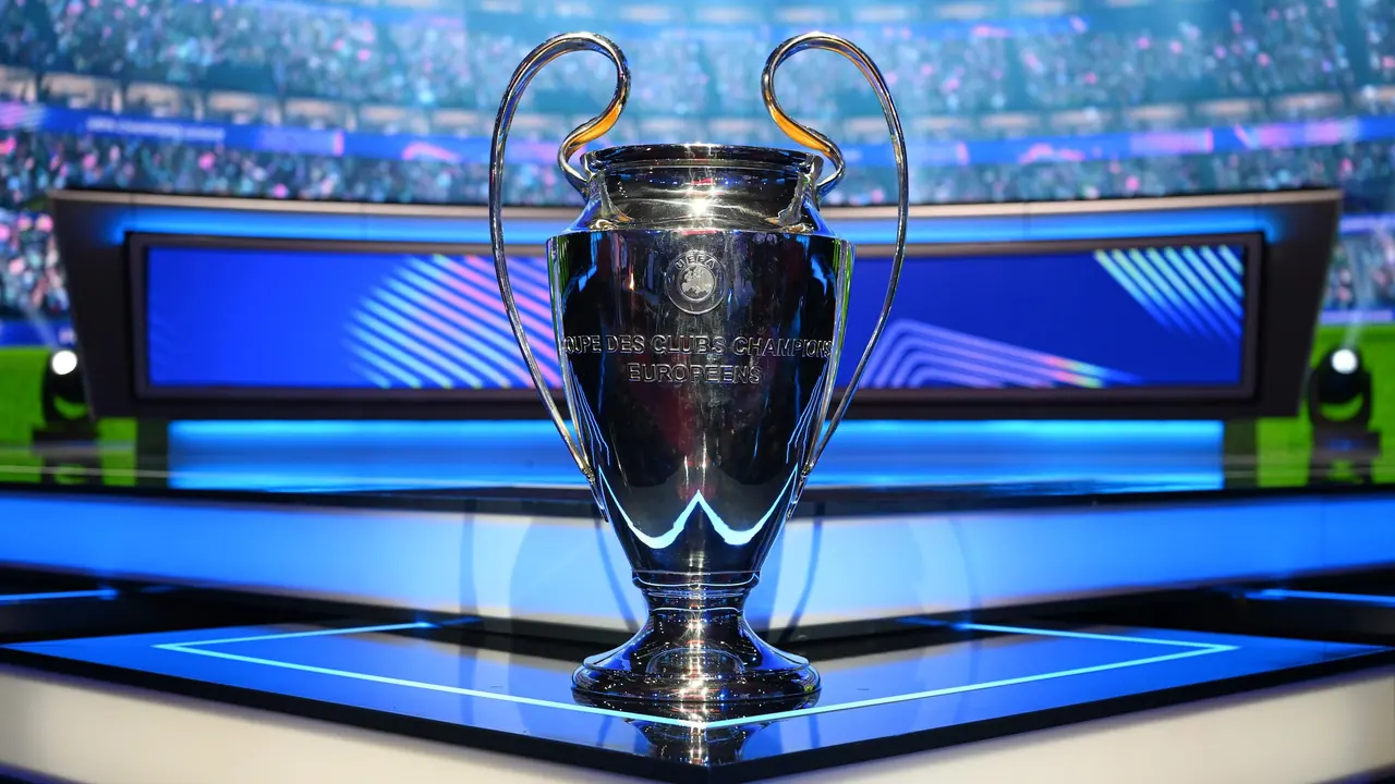 Troféu prateado da Champions League sobre um pedestal no cenário do sorteio em Mônaco.